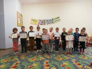 Grupa przedszkolaków trzymająca w rękach swoje prace