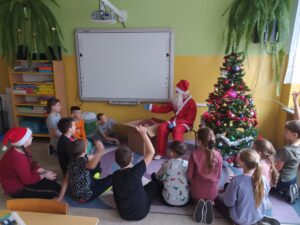 Zdjęcie przedstawia Mikołaja ,który rozmawia i rozdaje prezenty dzieciom.