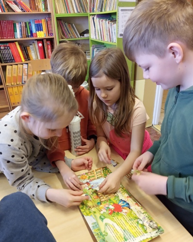 Biblioteka. Uczniowie układają puzzle z bajkami.