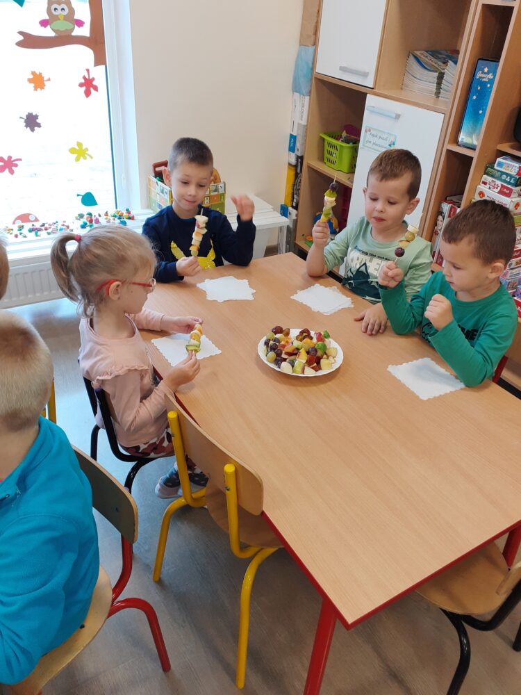 Dzieci wspólnie spożywają przyrządzone przez siebie owocowe posiłki