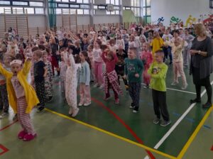 Dzieci w pidżamach wykonują ćwiczenia na sali gimnastycznej