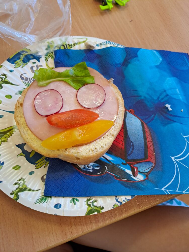 Kanapka z bułki, rzodkiewki i papryki w kształcie uśmiechniętej buźki