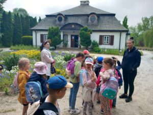 Dzieci słuchająopowieści przewodnika przed budynkiem muzeum