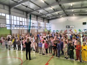 Społeczność szkolna ubrana w piżamy ćwicząca na sali gimnastycznej
