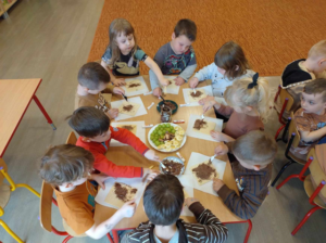 Przedszkolaki przy stoliku zajadające się czekoladą