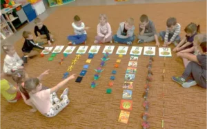 Przedszkolaki przyporządkowują liczby do odpowiedniej ilości danych przedmiotów na podłodze.