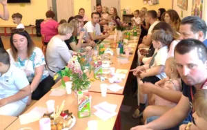 Rodzice razem z dziećmi siedzą przy wspólnym stole w przedszkolu