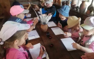 Przedszkolaki próbujące pisać gęsim piórem