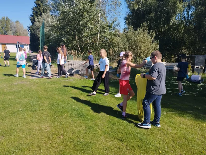 Dzieci sprzątają plac przy szkole